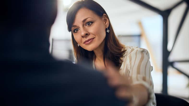 A lovely brunette female therapist listens and talks to a male client during psychotherapy.