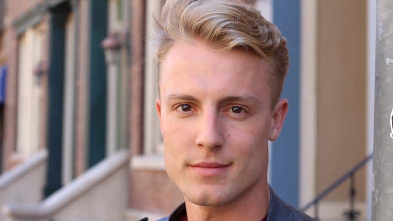 Close portrait of handsome adult blonde man, with blured urban classic background