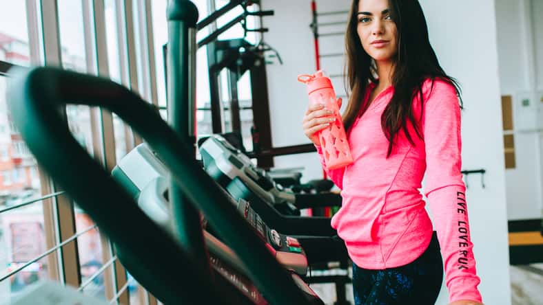 young girl at the gym trainer holding a bottle of water