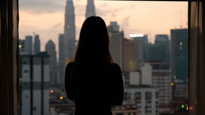 Silhouette of woman at sunset with city