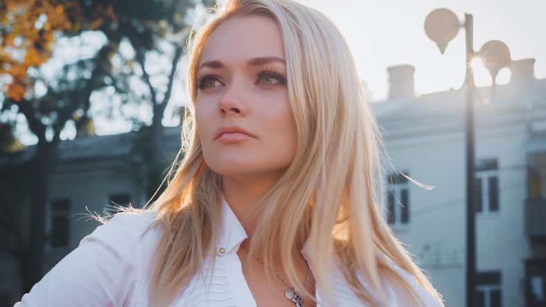 Portrait of young happy blonde business woman in the city. Beautiful girl in white sexy blouse in the street.