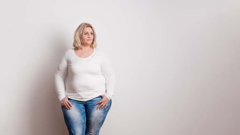 Portrait of an attractive blond overweight woman in studio on a white background. Copy space.