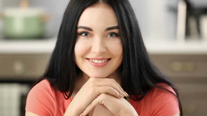 Portrait of young beautiful woman smiling in kitchen