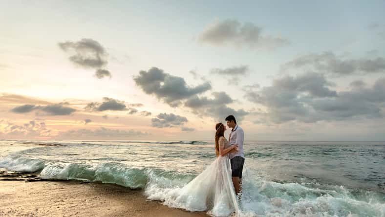 Bride and groom hugging on the beach standing in the sea water
