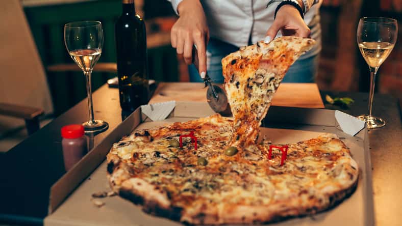 closeup of woman cutting pizza .