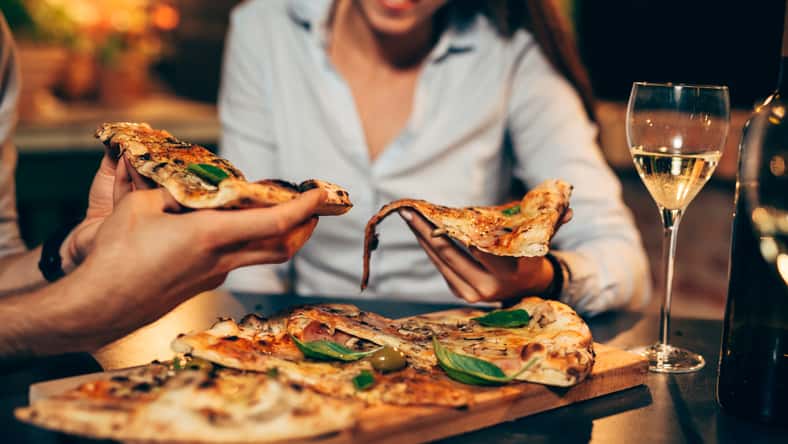 close up of people eating pizza.