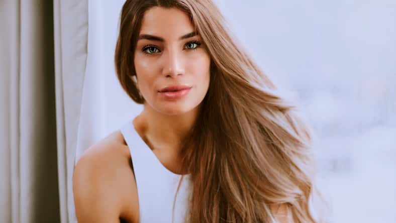 Pretty young long hair female brunette in front of the window
