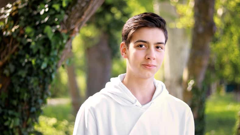 Portrait of handsome shy teenager boy in park outdoors. Natural light. Adolescent boys