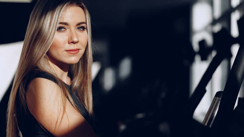 Close up portrait of a beautiful blonde woman with long hair smiling in dark room