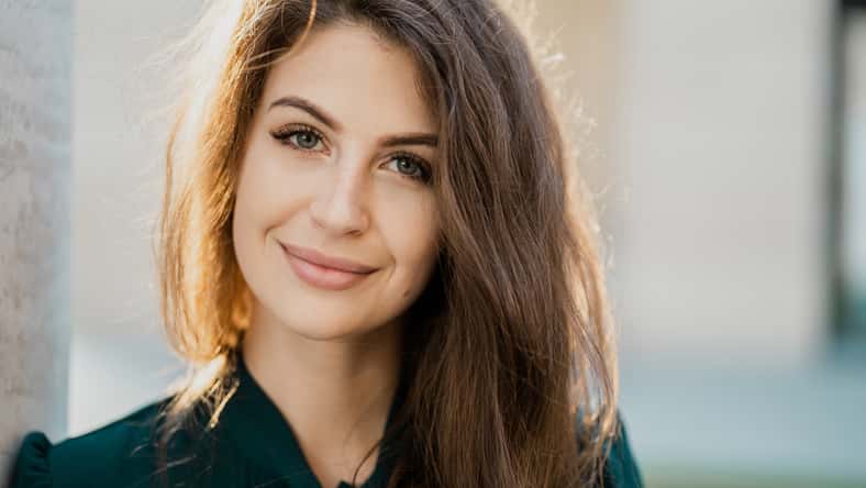 business woman confident smart teacher management student brunette of European appearance standing on the street smiling in a green dress and looking at the camera. Sunny day business center