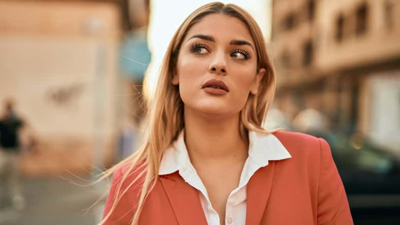 Young blonde businesswoman with serious expression standing at the city.
