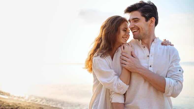 Smiling young couple two friends family man woman 20s in casual clothes hug girlfriend put head on boyfriend shoulder at sunrise over sea sand beach ocean outdoor seaside in summer day sunset evening