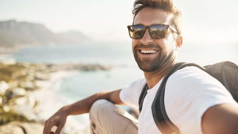 Retrato recortado de un joven guapo tomando selfies mientras camina en las montañas.