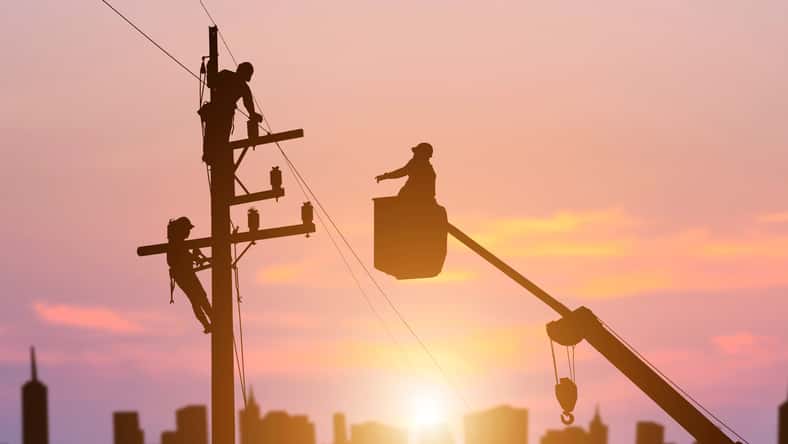 silhouette electrician working on high voltage pole install equipment