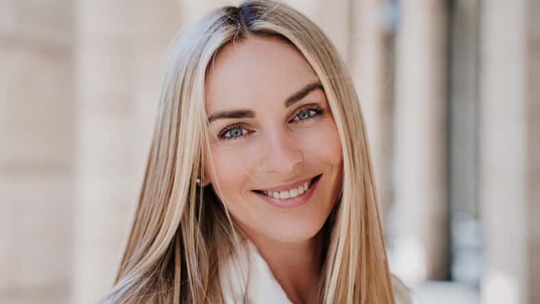 Close up portrait of blonde happy entrepreneur with toothy candid smile, Italian young businesswoman happy to be successful, looking at camera. Cheerful caucasian female satisfied by her life.