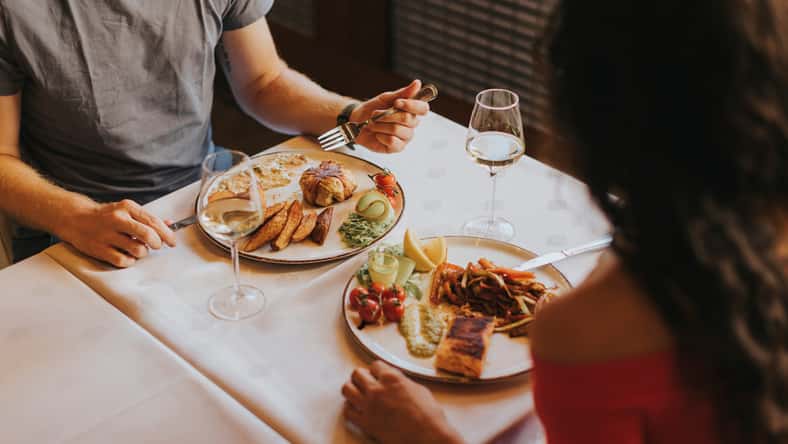 Handsome young couple having lunch with white wine in the restaurant