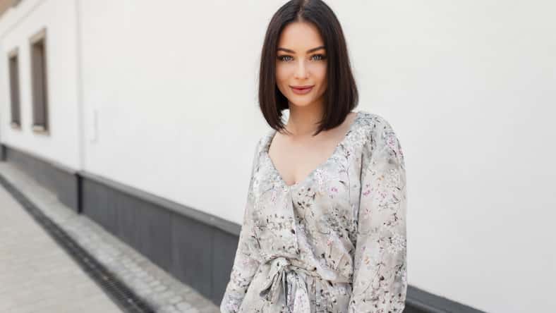 Urban female summer portrait of beautiful woman with hairstyle in fashion spring flowers dress walks in the city