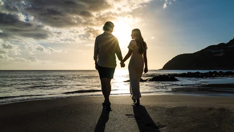 silhouette of young engaged couple holding hands in love during the sunset on a sandy island beach