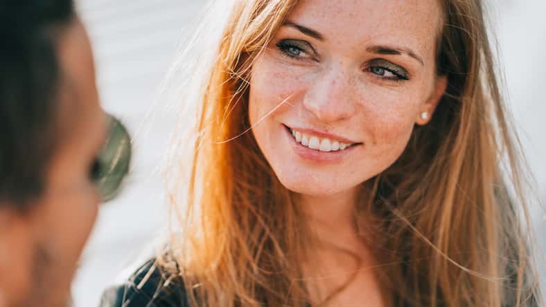 Close up redhead American woman toothy smiles looks at boyfriend tenderly, Couple in love dating. Happy caucasian girl looking at husband, feels love. Newlyweds at travel. Romance, relationship.