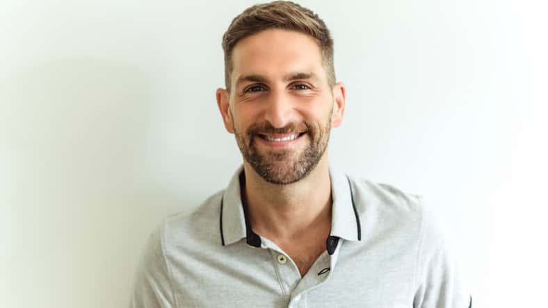 A Close-up daylight portrait of young smiling handsome man isolated on gray background
