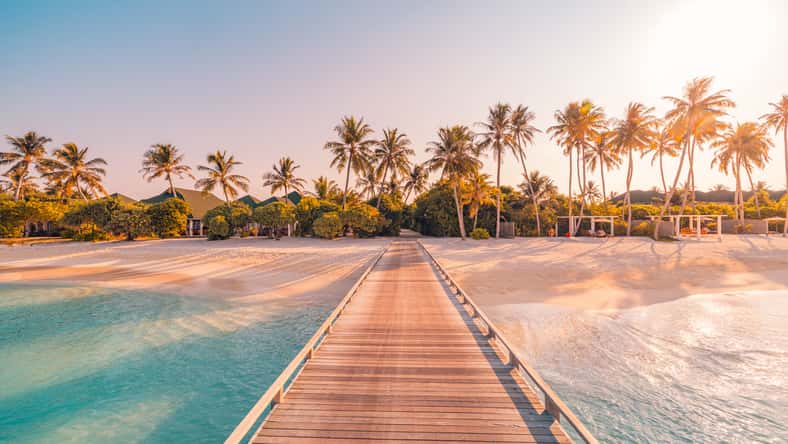 Amazing sunset panorama at Maldives. Luxury resort villas seascape with soft led lights under colorful sky. Beautiful twilight sky and colorful clouds. Beautiful beach background for vacation holiday
