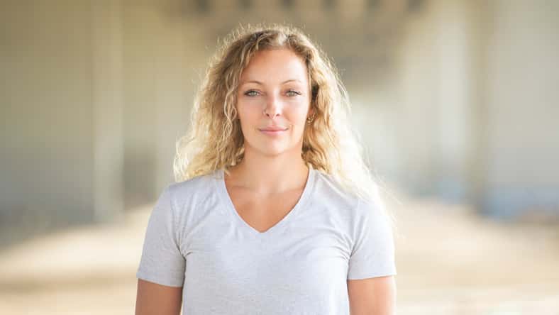 A portrait caucasian woman with fresh and clean skin stands outside on industrial background