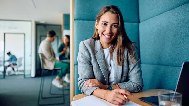 Happy female entrepreneur working in office and looking at camera.