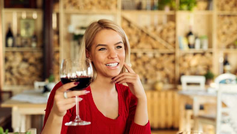 Attractive beautiful young woman tasting wine and