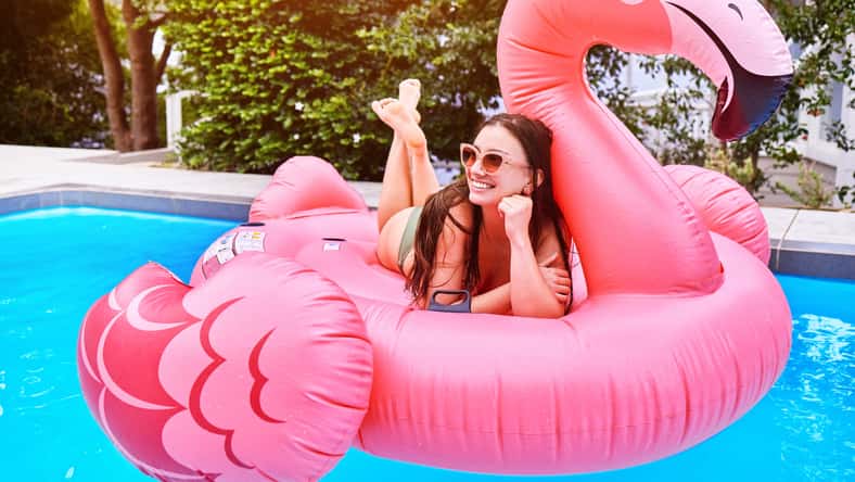 Happy girl, relax and pool with flamingo