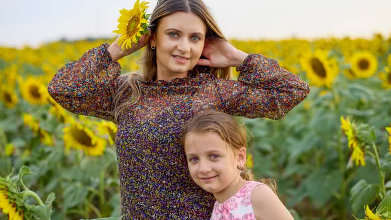 A mother with her little girl on a farm enjoying a sunflower field on a summer day