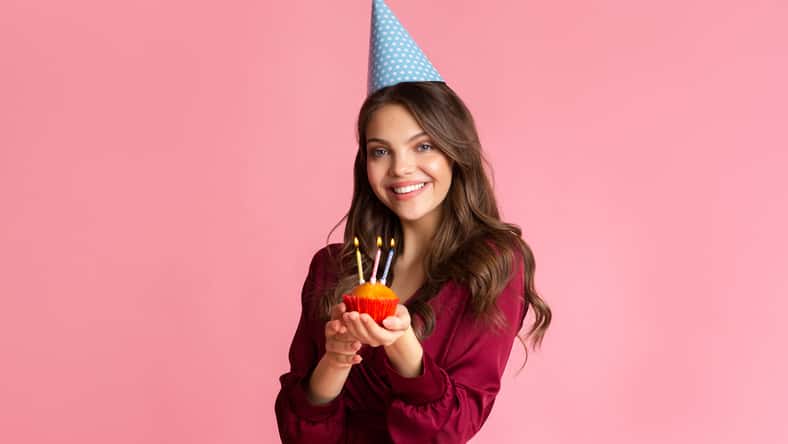 Happy young woman in party hat holding