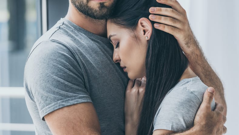 disparo recortado de hombre barbudo abrazando y apoyando a la joven triste mujer triste