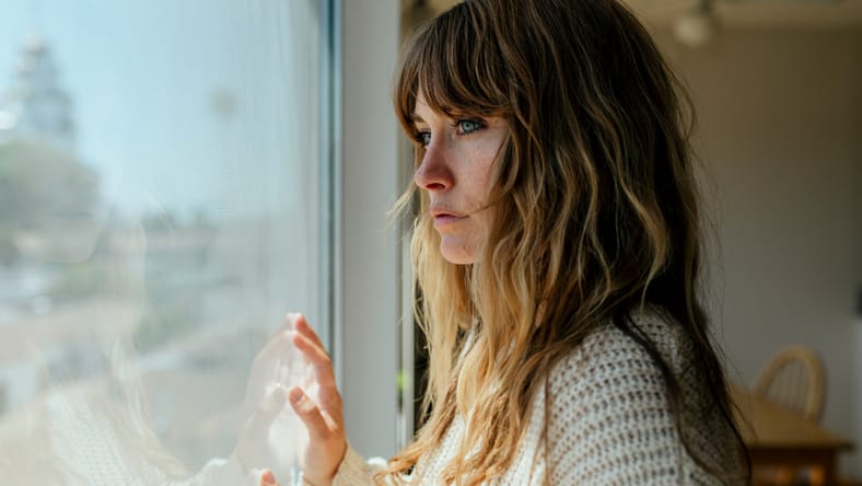 Mujer triste mirando por la ventana durante un bloqueo