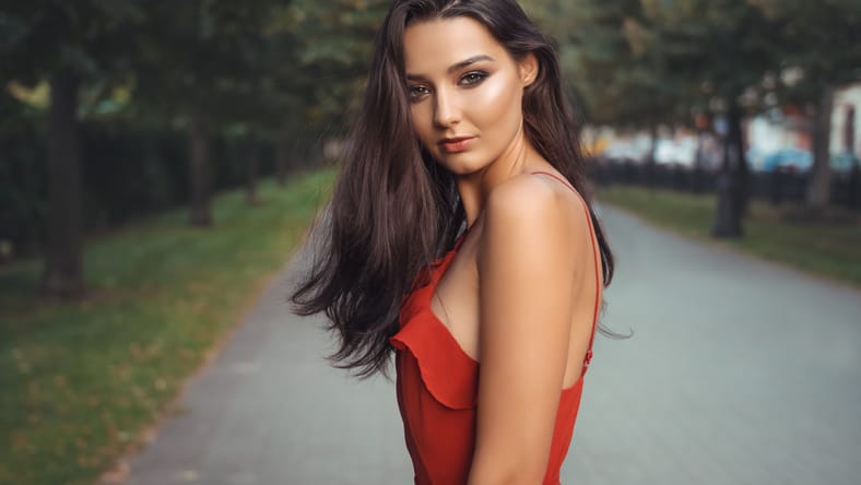 Foto al aire libre de atractiva modelo morena con vestido rojo