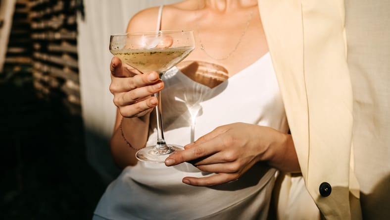 Mujer lujosa con un vestido blanco, sosteniendo un coupé con cham