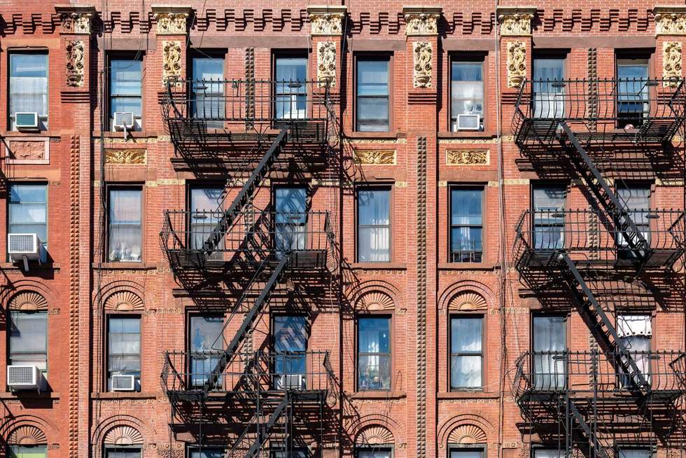 A close up of a typical Harlem residential building with red brick and decorative details over the windows.