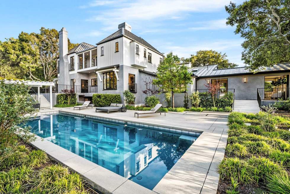 a home with a swimming pool surrounded by trees and lawns