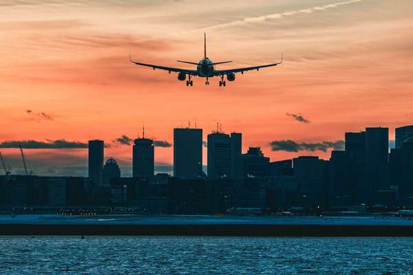 a plane landing in a city at sunset