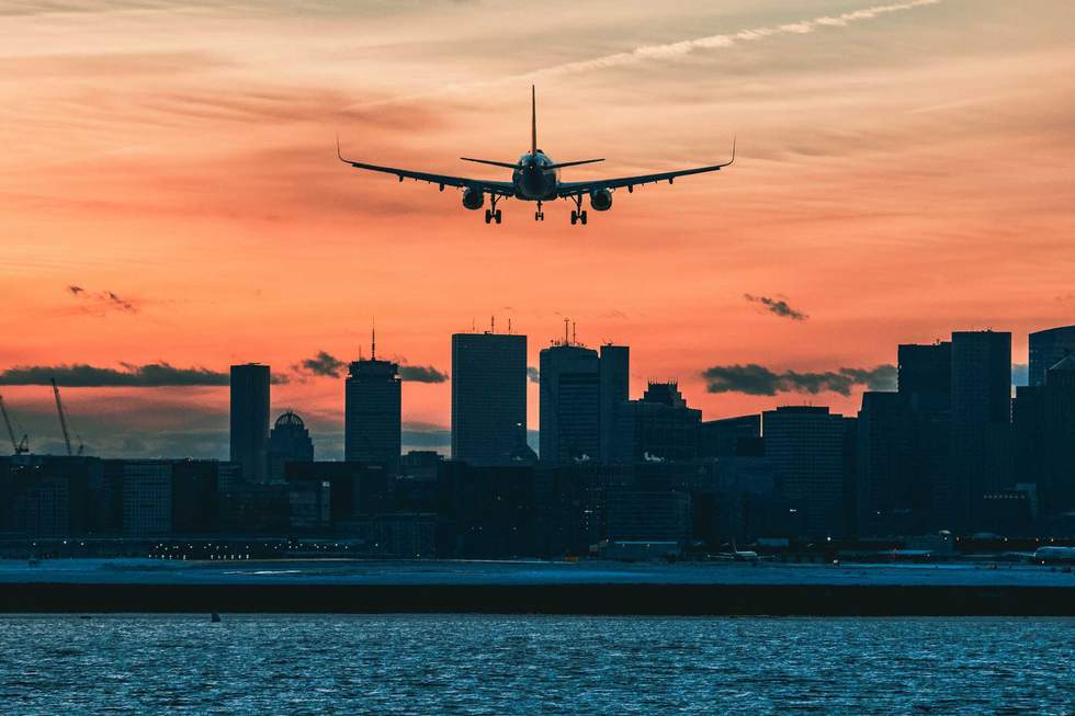 a plane landing in a city at sunset
