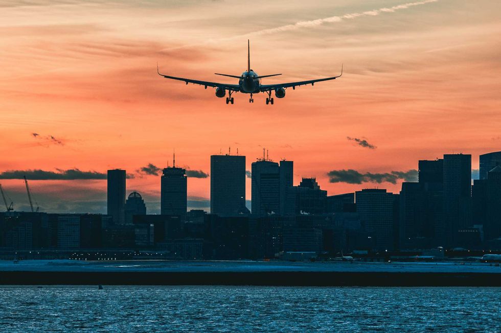 a plane landing in a city at sunset
