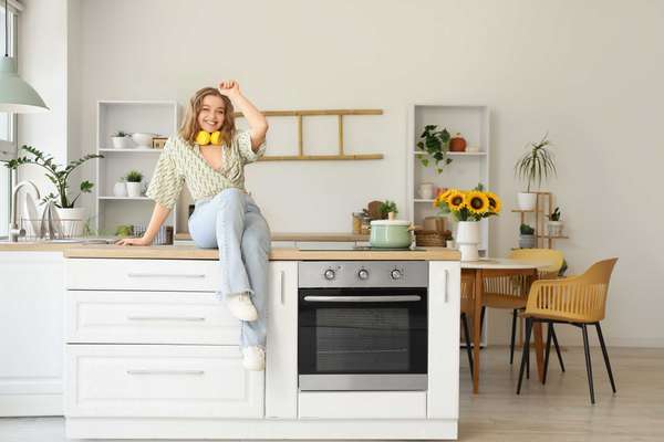 a woman sitting on the kitchen counter listening to music