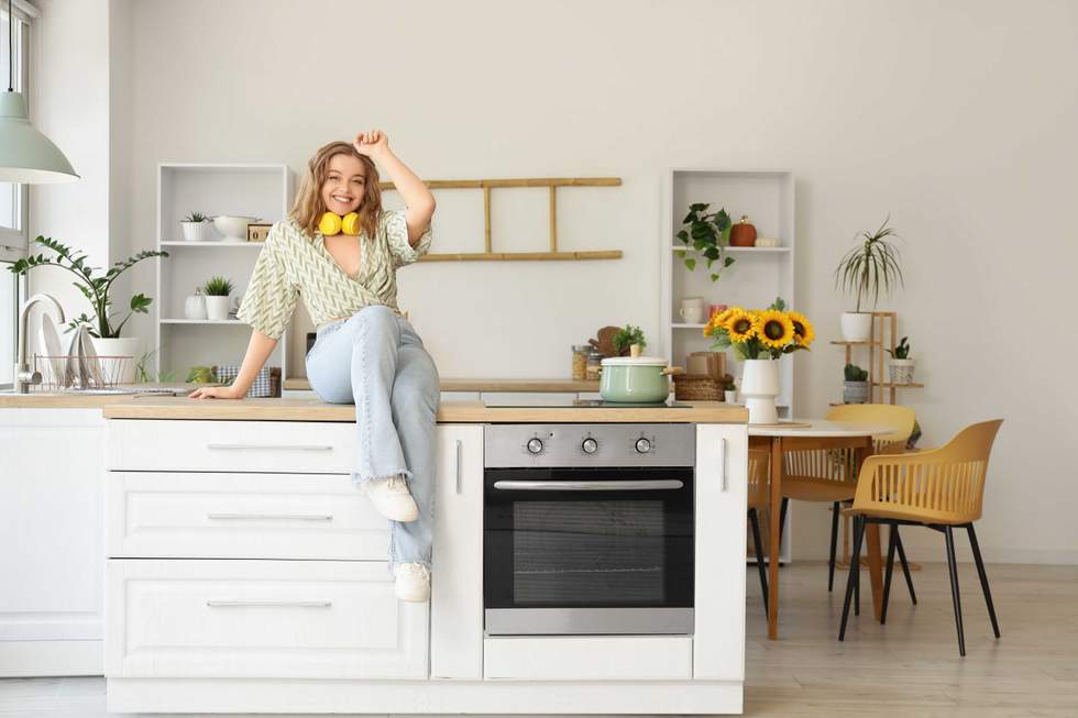 a woman sitting on the kitchen counter listening to music