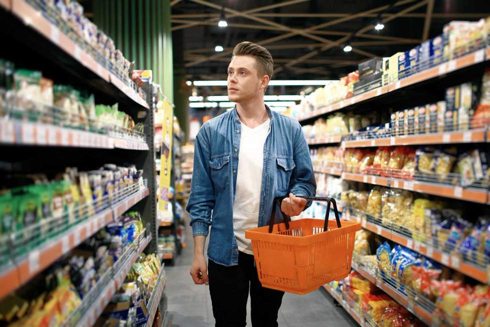 a young man chooses foods at the supermarket