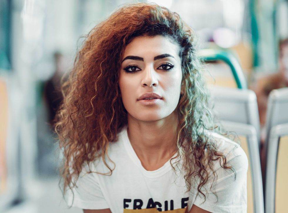 Arabic woman sitting inside subway train. Arab girl in casual clothes near a window.