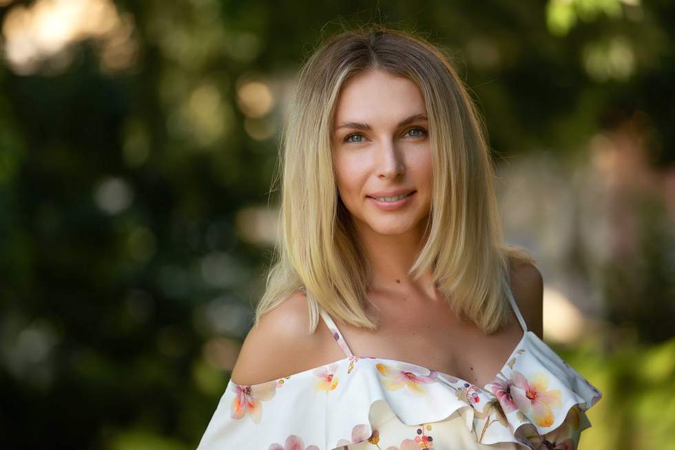 Attractive young blonde woman in a light summer dress with flowers