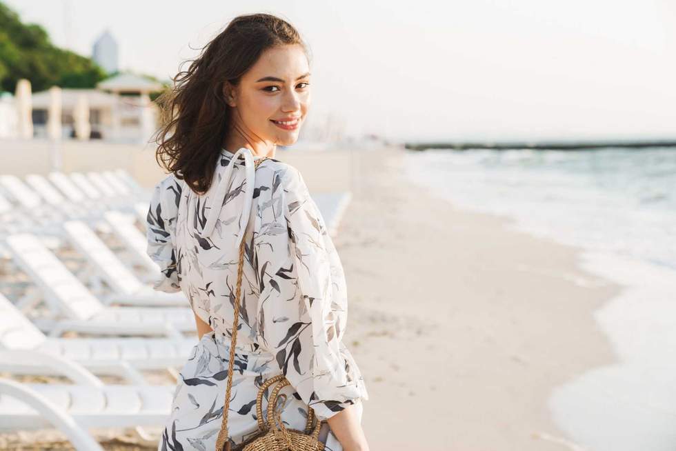 Back view image of a pleased happy young beautiful woman at the beach running in a beautiful sunny morning.