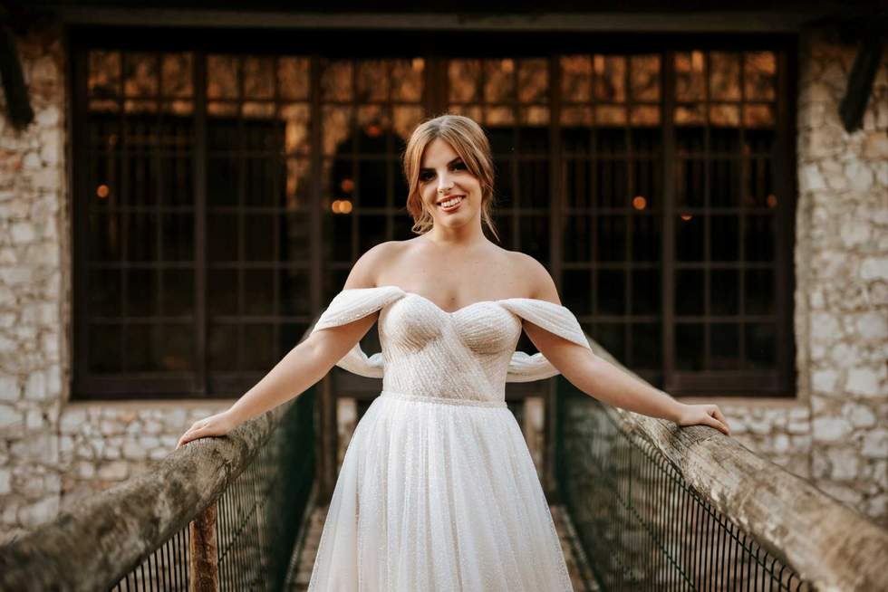 Beautiful bride portrait standing on wooden bridge with stone house behind