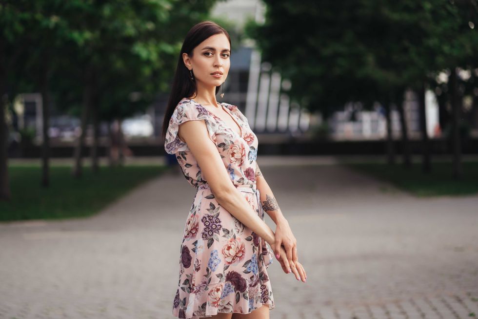 Beautiful girl in pink dress with flowers posing outdoors on summer day. Fashion city photo