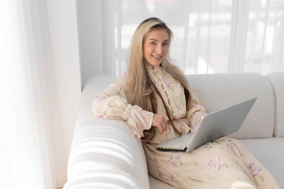 beautiful young happy woman with laptop on sofa