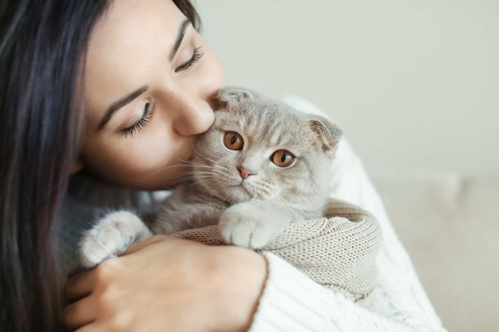 Beautiful young woman with cute cat resting at home